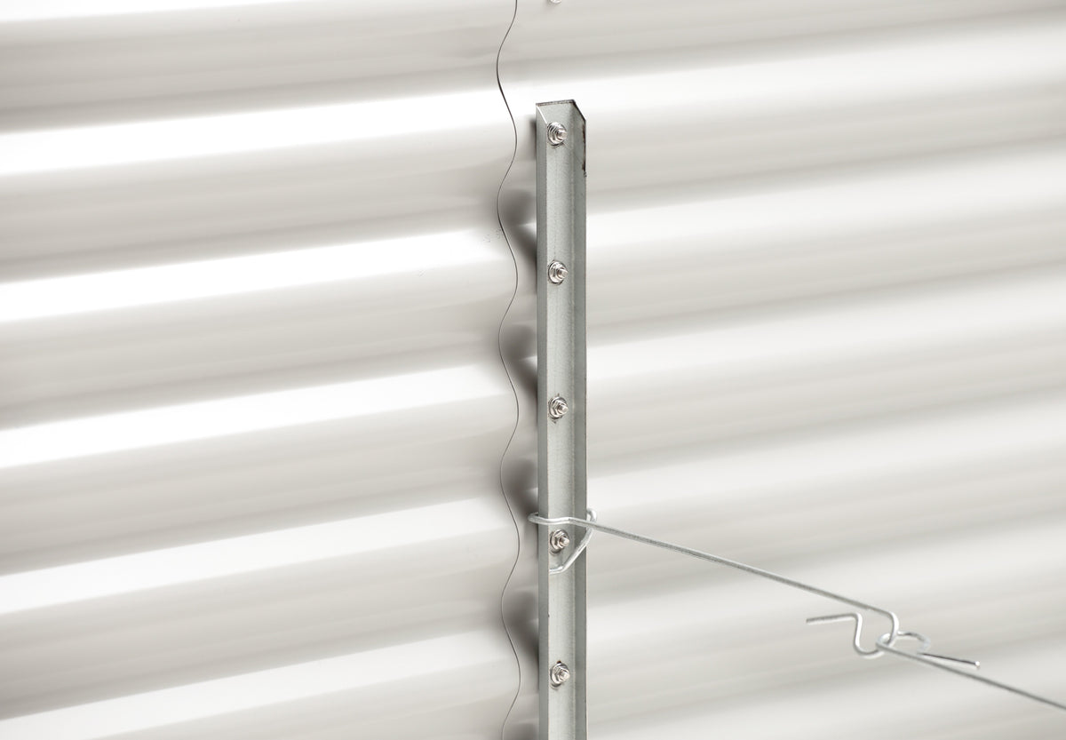 Metal bracket attached to a white corrugated metal wall