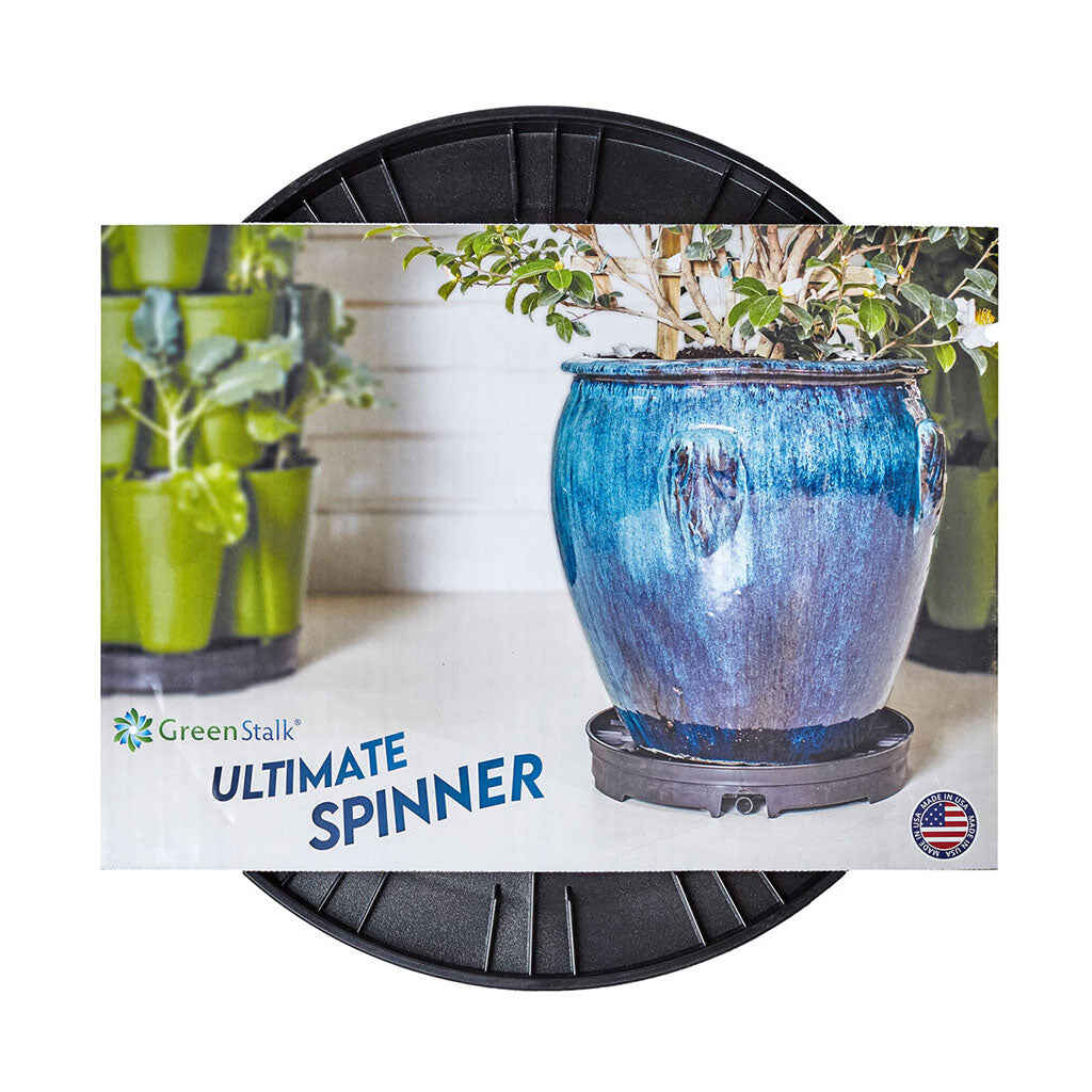 GreenStalk Ultimate Spinner, a round black wheeled rotating base, shown on packaging featuring a large blue-glazed planter and a stacked green tiered garden tower, with text noting it is made in the USA.