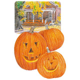 Illustration of three carved jack-o'-lantern pumpkins with triangular eyes and toothy grins, set against a small inset scene of a brick porch heaped with pumpkins beneath an autumn tree.