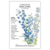 Seed packet for Shades of Blue Larkspur showing an illustration of tall spires with deep blue to pale blue-white bell-shaped flowers on slender green stems, with text noting it's a full-sun annual blooming spring to summer, growing 3'–4' tall, suited for cut and dried arrangements.