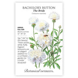Seed packet for The Bride Bachelor's Button (Centaurea moschata) featuring an illustration of fluffy, vanilla-white fringed blooms with yellow centers and a visiting bee on tall green stems, with text noting it's an annual for full sun, blooming summer at 32 to 36 inches tall.