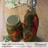 A mason jar and a swing-top glass bottle filled with pickled green and red chile peppers in brine, sitting on a wooden countertop beside scattered seed packets, with text captioning them as Scotch Bonnet and Early Jalapeño peppers.