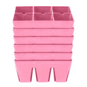 Six pink plastic six-cell seed starting trays stacked in a tower, each tray divided into six deep square compartments for individual seedlings.