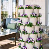 Seven-tier stone-colored GreenStalk Vertical Planter Basketweave filled with colorful blooming purple and yellow flowers, positioned on a patio next to outdoor furniture.