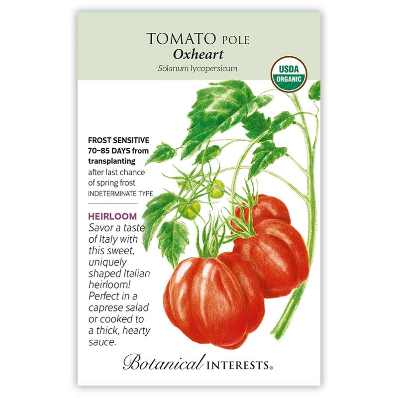 Seed packet for Botanical Interests Oxheart Pole Tomato, illustrated with heart-shaped, ribbed red fruit and green foliage on the vine, labeled USDA Organic and heirloom, with text noting frost sensitivity, 70-85 days from transplanting, and indeterminate growth type.