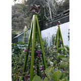 Olive green pyramid-shaped metal Akoris Garden Obelisk Large trellises with bronze sphere finials set among lush green foliage and purple flowering plants