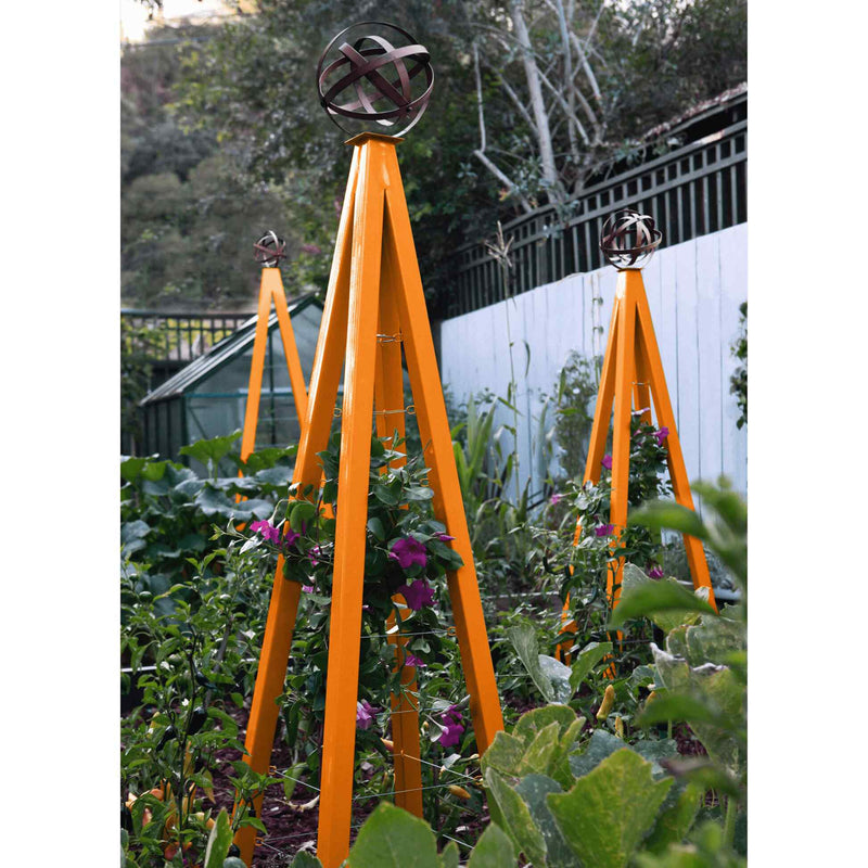 Orange pyramid-shaped metal Akoris Garden Obelisk Large trellises with bronze sphere finials set among lush green foliage and purple flowering plants