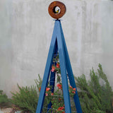 Blue metal A-frame Bird Cafe with Trellis topped with a circular oxide steel bird feeder, set against a concrete wall with rosemary plants at the base
