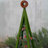 Olive green A-frame Bird Cafe with Trellis topped with a circular oxide steel bird feeder, set against a concrete wall with rosemary plants at the base