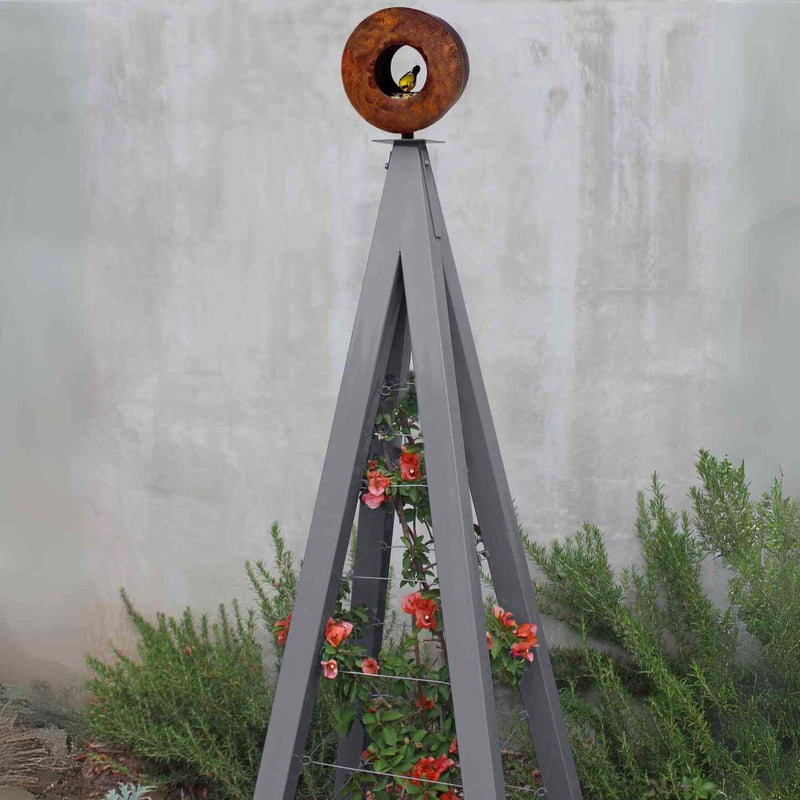 Dark gray metal A-frame Bird Cafe with Trellis topped with a circular oxide steel bird feeder, featuring orange flowers climbing the trellis