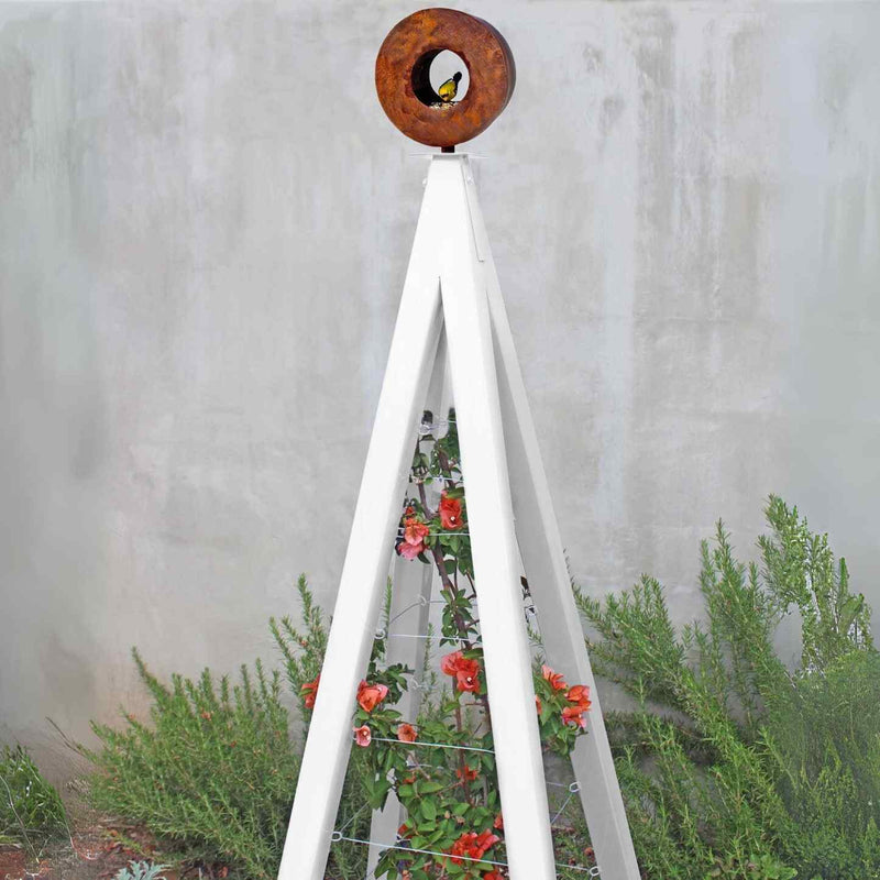 White metal A-frame Bird Cafe with Trellis topped with a circular oxide steel bird feeder, featuring orange flowers climbing the trellis