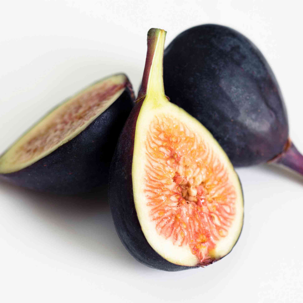 Whole and sliced ripe Black Mission Figs showing rich dark purple skin and vibrant pinkish-red interior flesh.