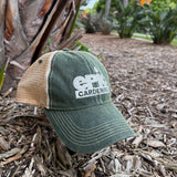 Green Epic Gardening cap resting on soil in a garden.