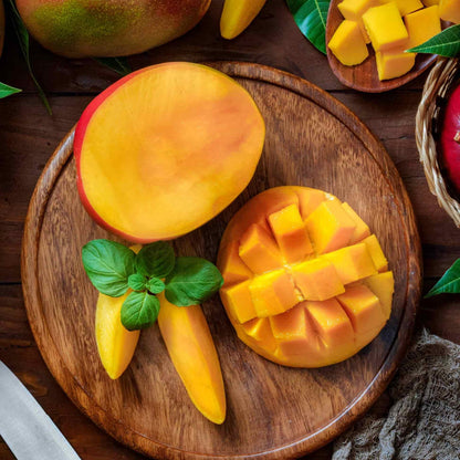 Freshly sliced and scored Glenn Mango halves served on a round wooden cutting board.