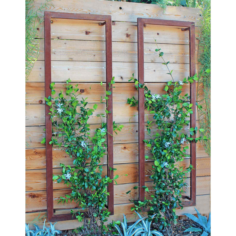 Two zinc metal rectangular Ina Wall Trellises mounted on a light wood wall with flowering vines climbing through their wire grids