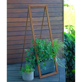 Rust-finished A-frame Mira Garden Trellis supporting lush green potted plants against a dark wood wall