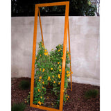 Orange metal frame A-frame Mira Garden Trellis with black-eyed Susan vines climbing up the grid wire, positioned in front of a concrete wall