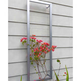 Silver tall rectangular Ina Wall Trellis mounted on a gray siding wall with bright pink bougainvillea flowers climbing through its wire grid