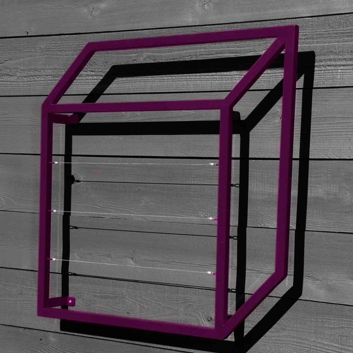 Purple cubic steel Pablo Wall Trellis mounted on a horizontal wood panel wall, throwing geometric shadows