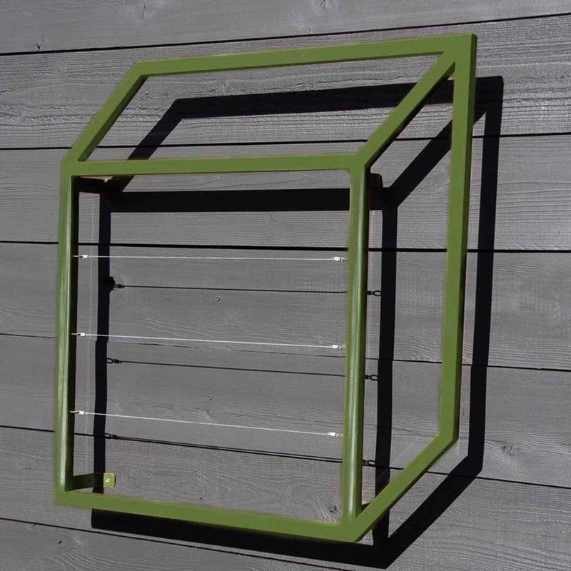 Green powder-coated cubic metal Pablo Wall Trellis mounted on a wooden wall, casting a geometric shadow
