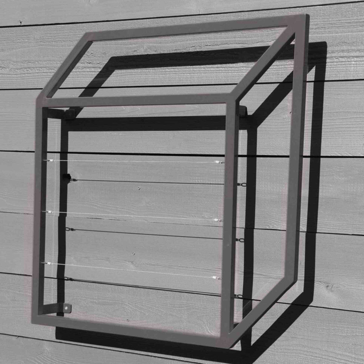 Gray cubic metal Pablo Wall Trellis mounted on a horizontal wood panel wall, throwing geometric shadows