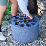 Person placing a multi-hole Plantable Fabric Cover on a felt grow bag.