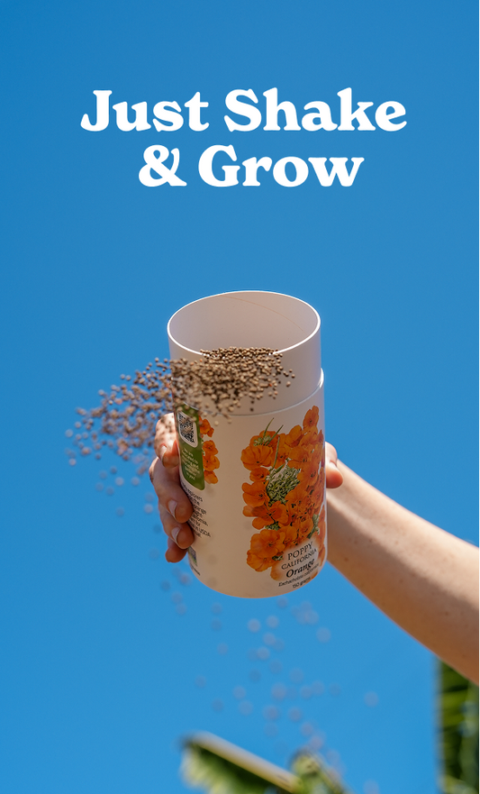 Hand holding a Botanical Interests California Orange Poppy seed shaker canister upright while scattering seeds against a bright blue sky, with white text above reading "Just Shake & Grow".
