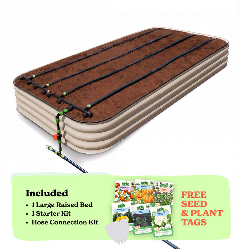 A raised garden bed in light clay color filled with soil, shown with drip irrigation tubing laid across the top. A light green promotional banner at the bottom lists included items: 1 15-inch tall large raised bed, 1 starter kit, and hose connection kit, with a small image of seed packets and the text 'Free Seed & Plant Tags'.