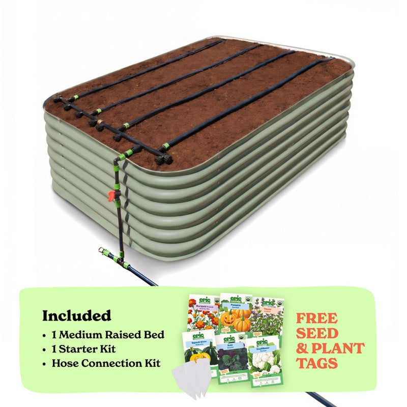 A raised garden bed in mist green color filled with soil, shown with drip irrigation tubing laid across the top. A light green promotional banner at the bottom lists included items: 1 29-inch tall medium raised bed, 1 starter kit, and hose connection kit, with a small image of seed packets and the text 'Free Seed & Plant Tags'.