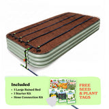 A raised garden bed in mist green color filled with soil, shown with drip irrigation tubing laid across the top. A light green promotional banner at the bottom lists included items: 1 15-inch tall large raised bed, 1 starter kit, and hose connection kit, with a small image of seed packets and the text 'Free Seed & Plant Tags'.