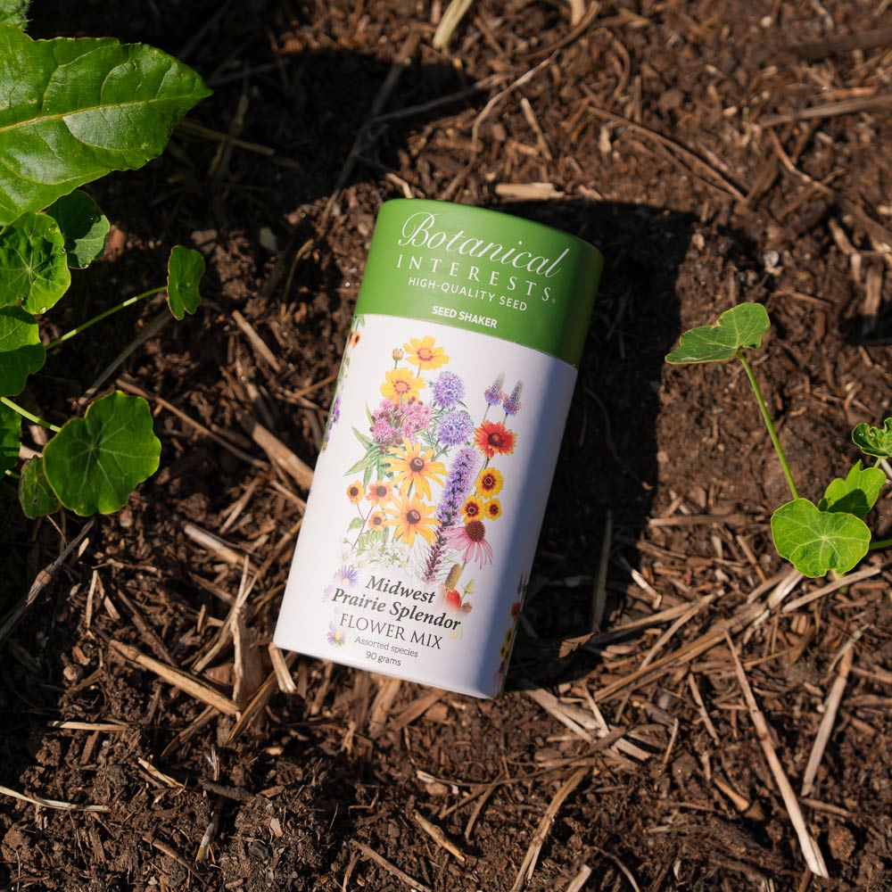 Botanical Interests Midwest Prairie Splendor Flower Mix Seed Shaker canister on soil with plants around