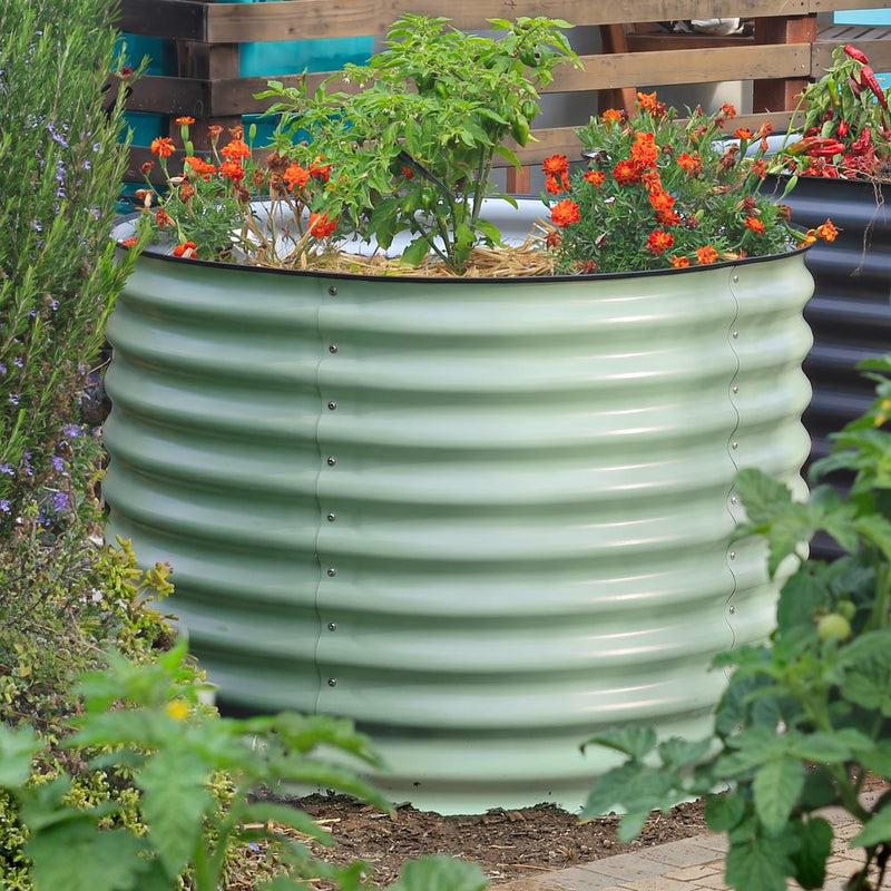 29-inch tall mist green green metal raised garden bed filled with green plants and bright orange flowers, situated in a garden setting.