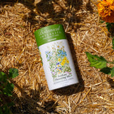 Botanical Interests EcoEase Flowering Mix Alternative Lawn Seed Shaker on straw with flowers in the background