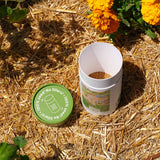 Opened container of the White Clover Alternative Lawn Seed Shaker with green lid on straw with marigold flowers