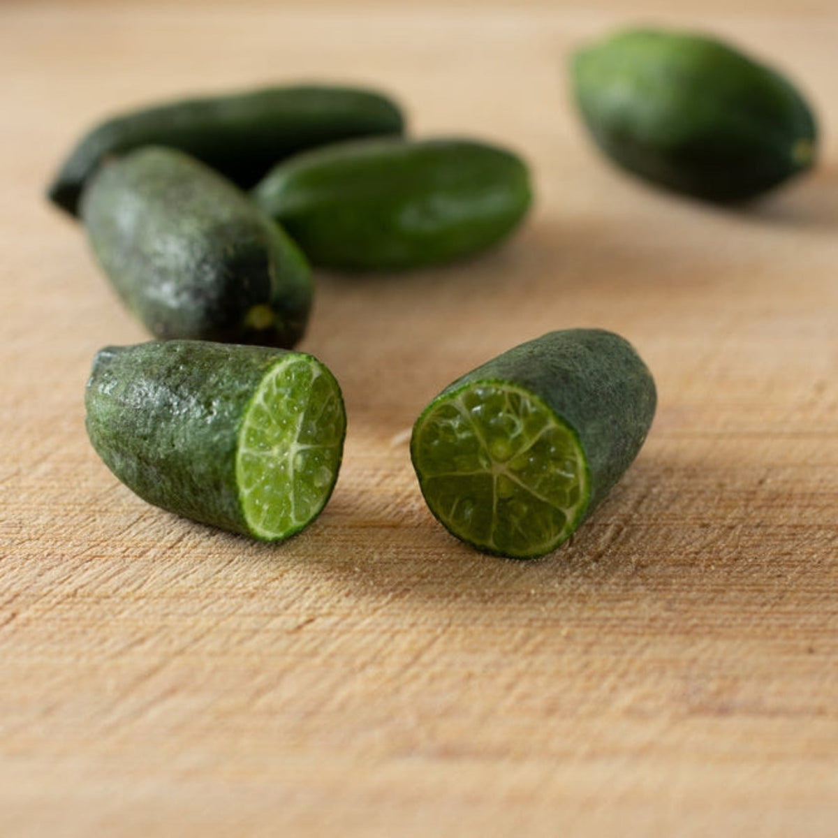 Australian Finger Lime fruit, one cut in half, on a wooden surface