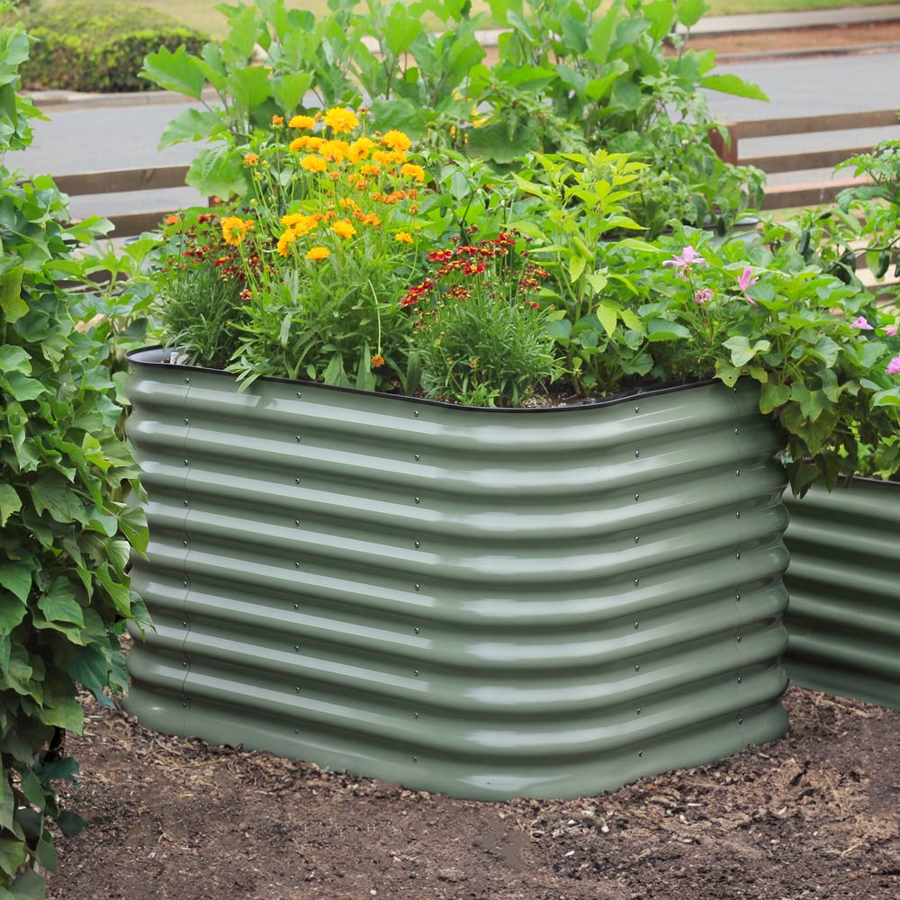 Mist green  29-inch tall small corrugated metal raised garden bed filled with green plants, yellow flowers, and small red flowers, shown in a garden setting.
