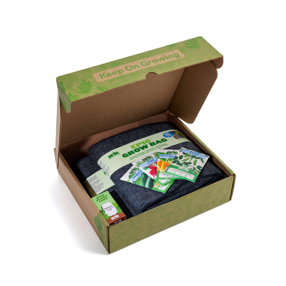 Open cardboard box of the "Snack Attack Epic Garden in a Box" containing a grow bag and seed packets with 'Keep On Growing' text.