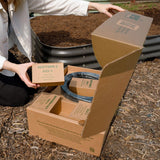Person opening a cardboard box with gardening epic irrigation components in an outdoor setting.