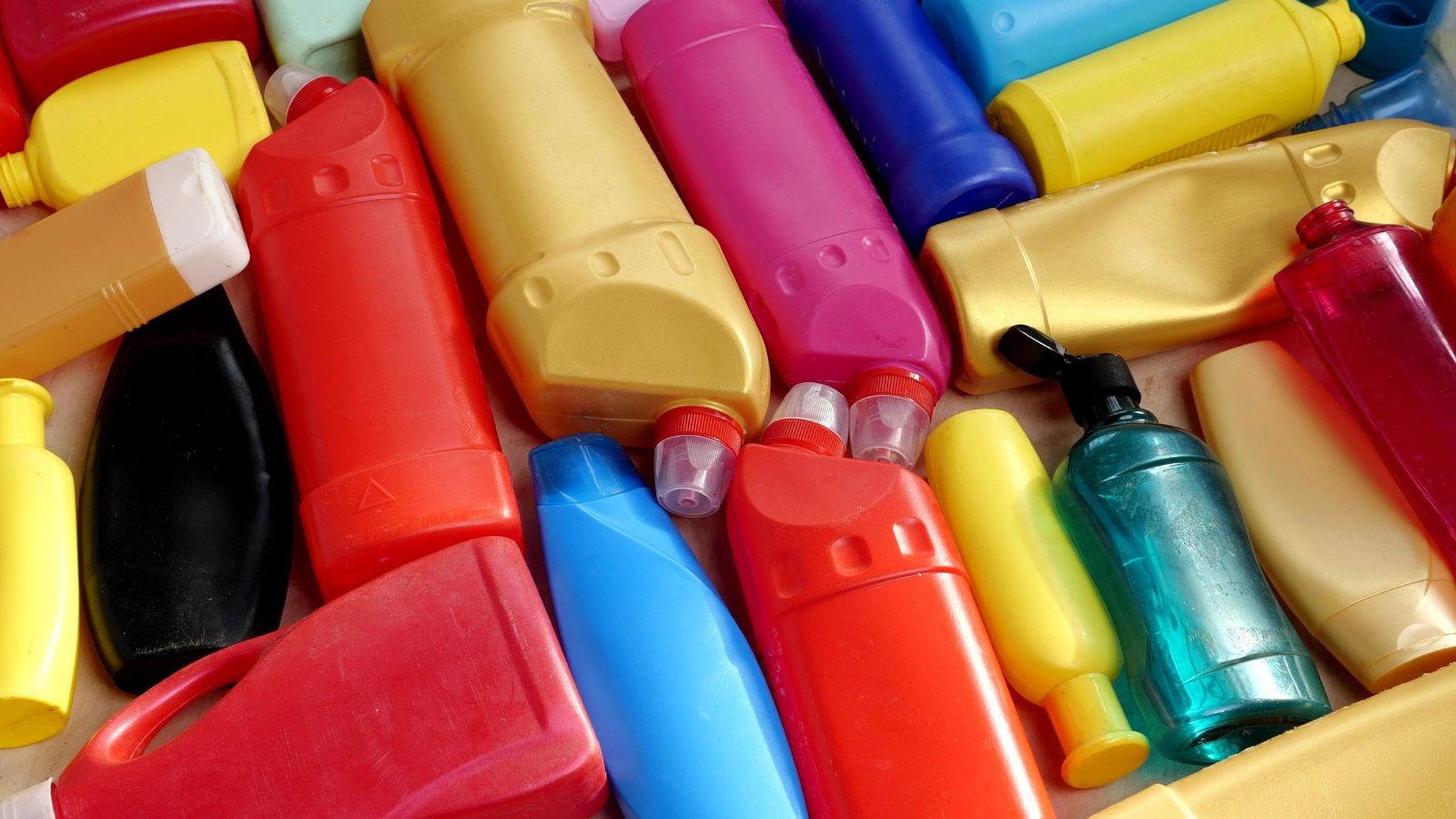 An overhead shot of a pile of several colorful HDPE container, placed in a box in a well lit area indoors