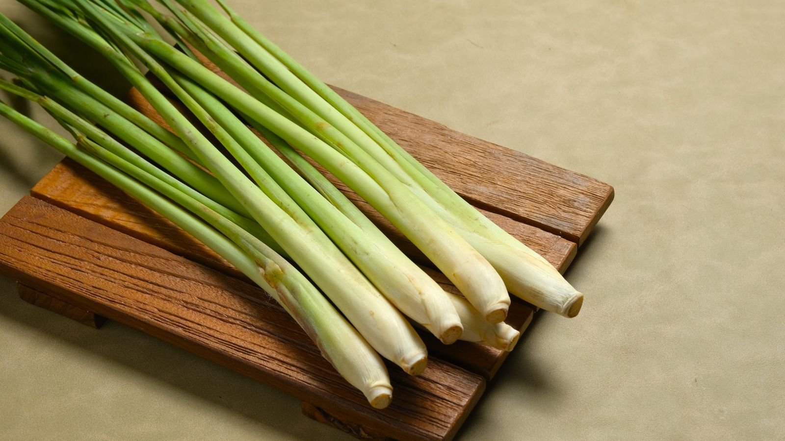 A close-up and overhead shot of a pile of fresh Lemongrass, all placed on a wooden surface indoors