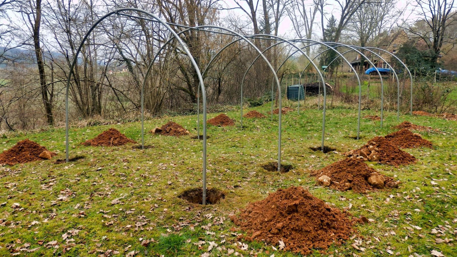 Poles forming a tunnel, built of steel poles driven into the ground with holes on the lawn surrounded by trees