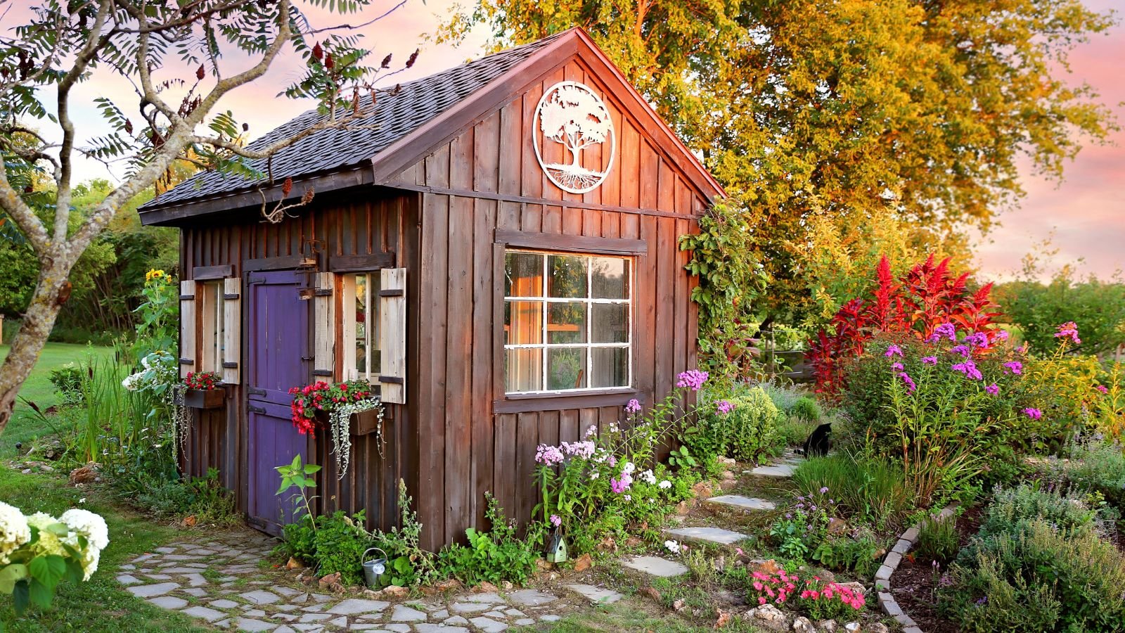 A tiny house with a lush and lovely garden, with the structure appearing to be made of wood surrounded by lovely plants