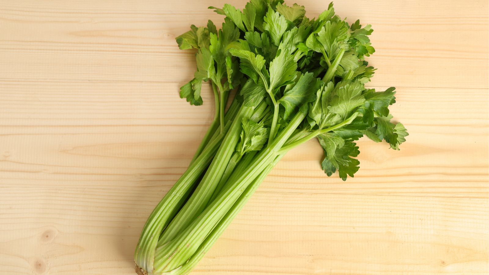 An overhead flat-lay shot of a fresh crop placed on a wooden surface in a well lit area indoors