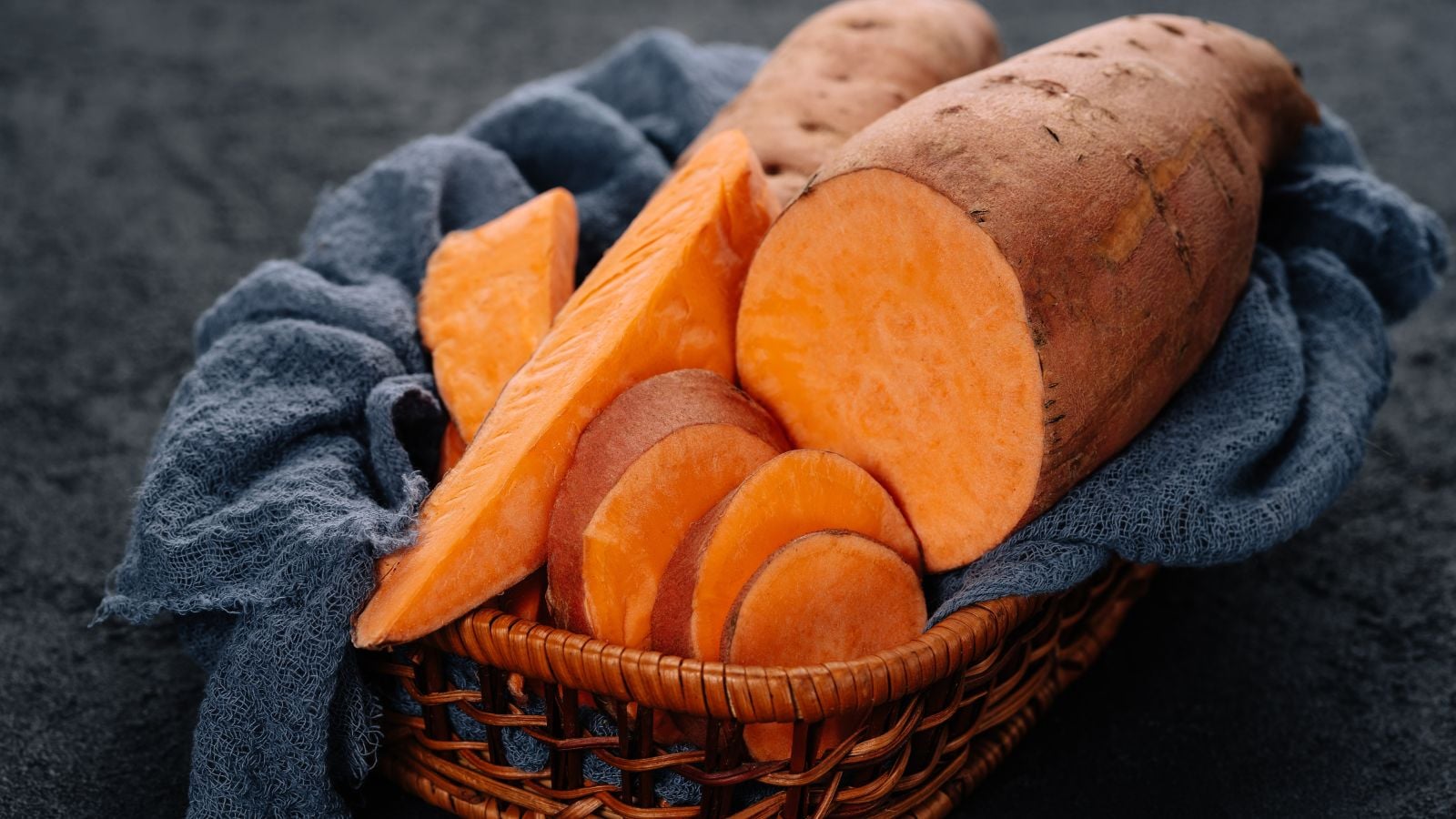 A close-up shot of a small pile of raw an uncooked slices of the Beauregard variety of crops, showcasing its copper skin and dark orange flesh