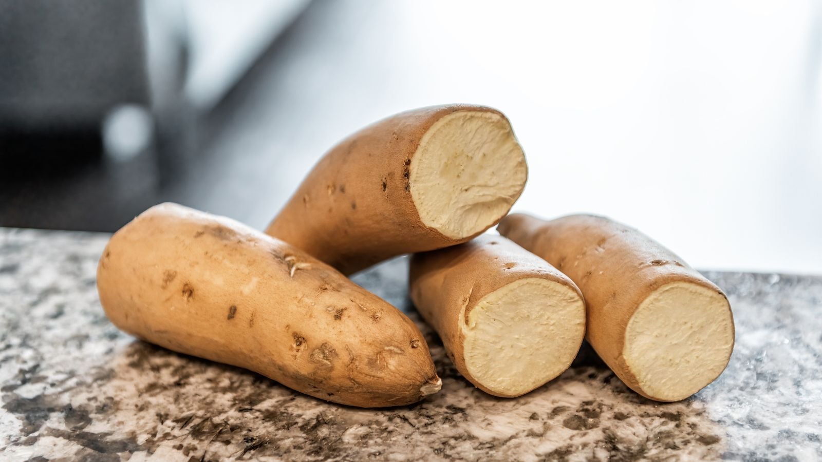 A close-up shot of a small pile of raw and uncooked Hannah variety of crops, showcasing their tan skin and cream colored flesh