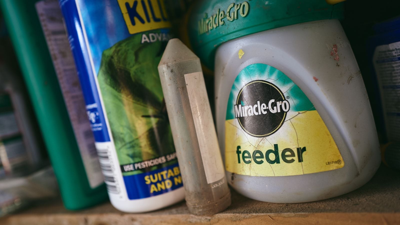 A shot of several containers of synthetic and organic fertilizers, placed in a wooden rack storage indoors