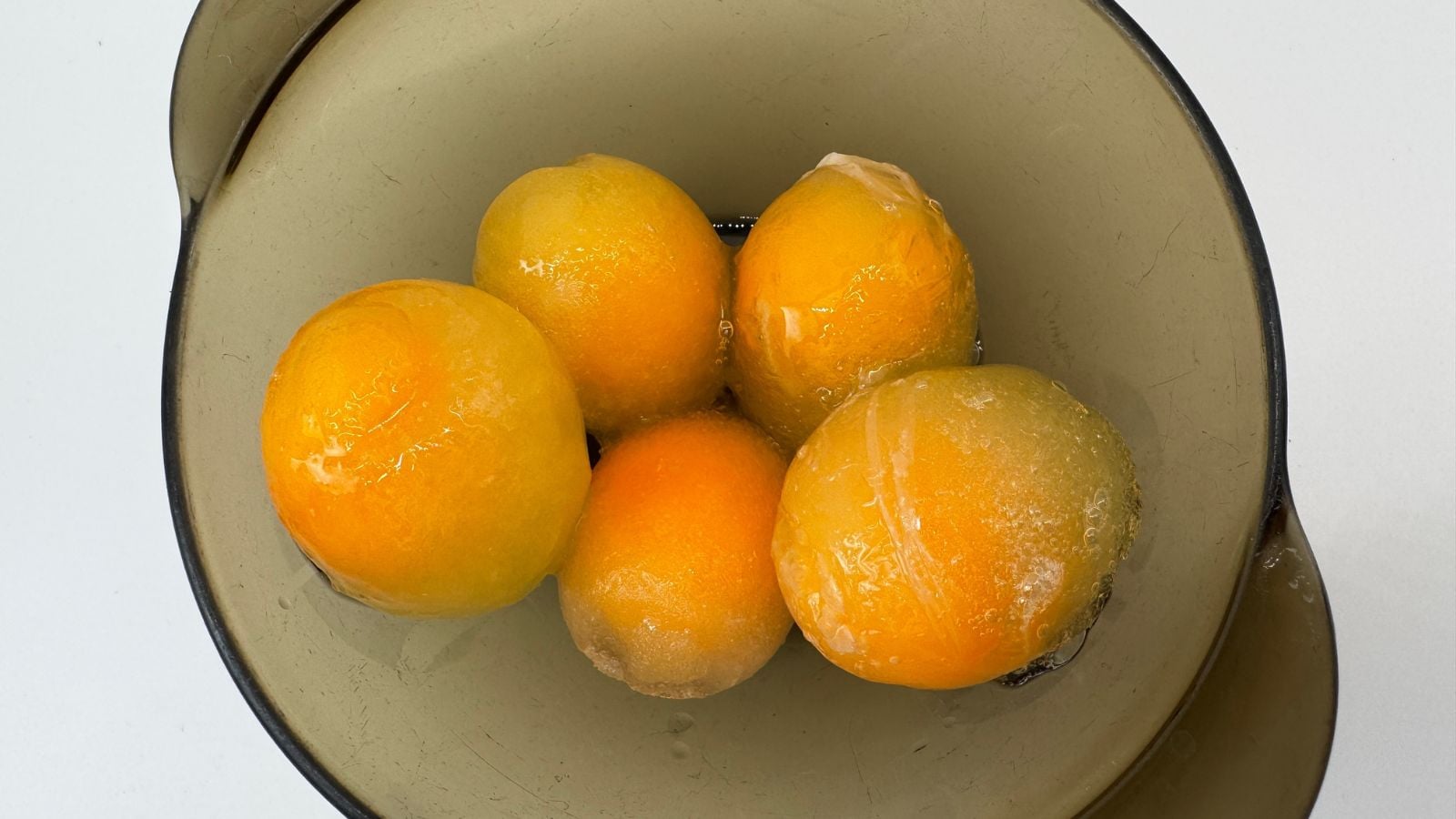 Eggs frozen and peeled inside a bowl set on a white surface that appears to be well lit