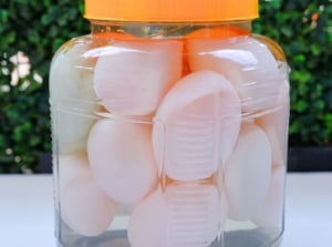 A photos showing the process of water glassing eggs, with the pieces inside a glass jar filled with clear liquid