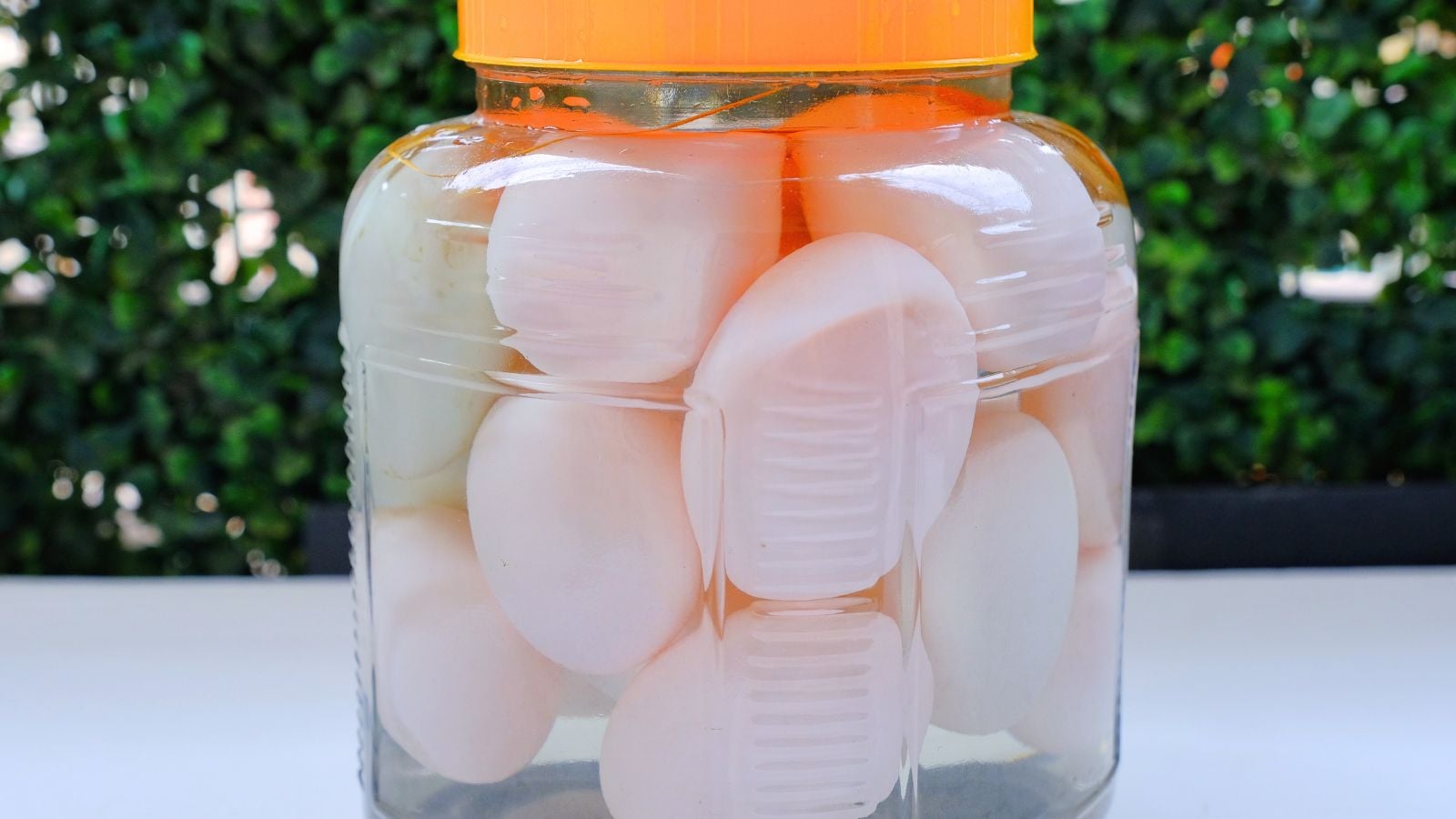A photos showing the process of water glassing eggs, with the pieces inside a glass jar filled with clear liquid