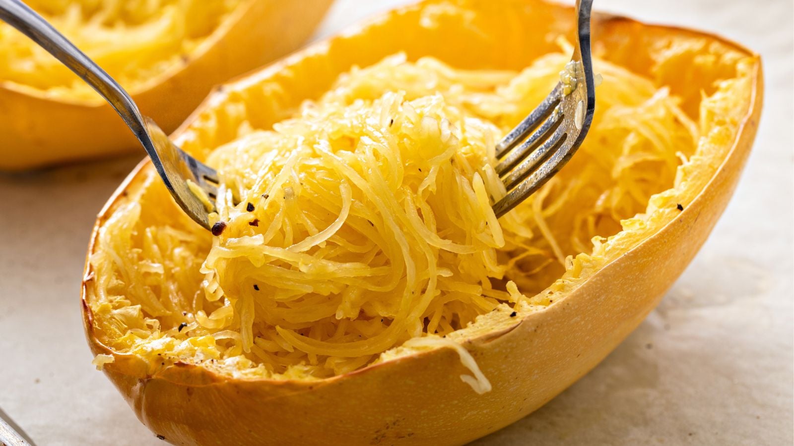 A sliced, cooked and grated Hasta La Pasta forming strands similar to pasta pieces being worked using two forks